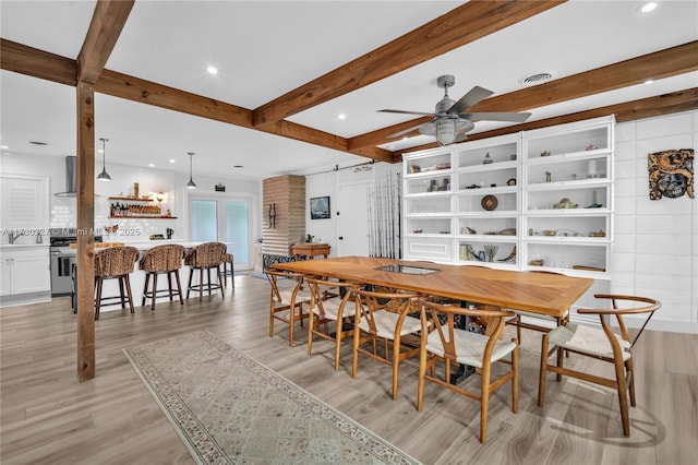 dining space with beamed ceiling, ceiling fan, and light wood-type flooring