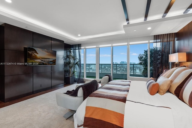 bedroom with recessed lighting, expansive windows, a raised ceiling, and wood finished floors