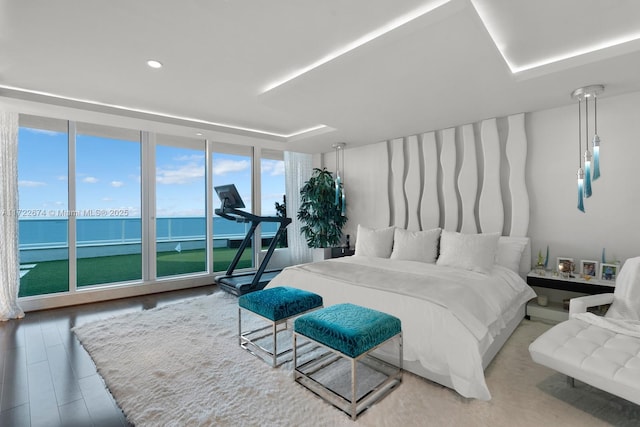 bedroom featuring a water view, floor to ceiling windows, and hardwood / wood-style floors