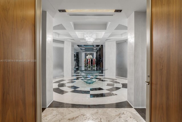 hall with coffered ceiling and an inviting chandelier