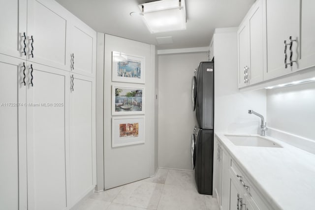 kitchen featuring sink, stacked washer / drying machine, and white cabinets