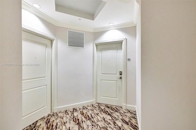 interior space with a tray ceiling, ornamental molding, and light wood-type flooring