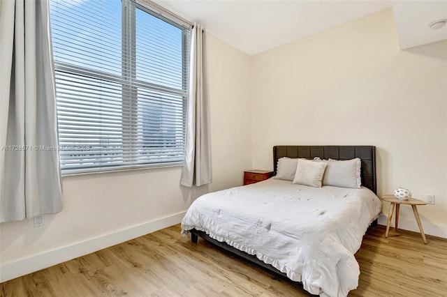 bedroom with multiple windows and light hardwood / wood-style flooring