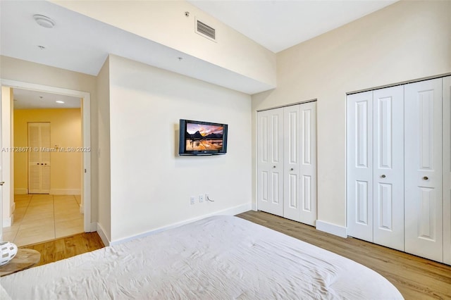 bedroom with hardwood / wood-style flooring and two closets