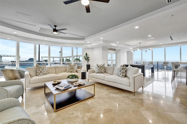 living room featuring a wall of windows, a tray ceiling, and a wealth of natural light