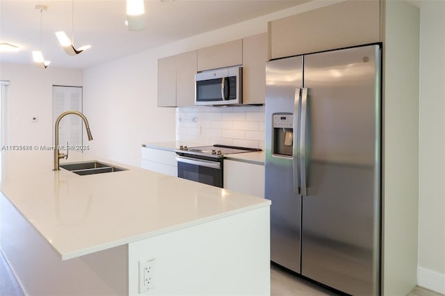 kitchen featuring tasteful backsplash, appliances with stainless steel finishes, sink, and hanging light fixtures