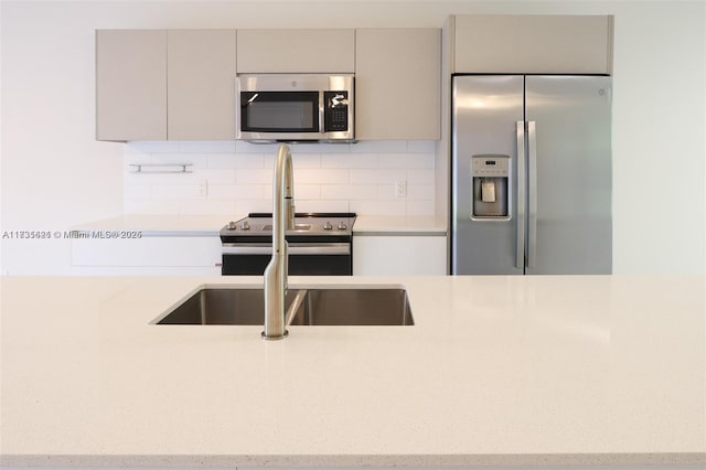 kitchen featuring sink, decorative backsplash, gray cabinets, and stainless steel appliances