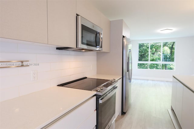 kitchen featuring stainless steel appliances, white cabinetry, tasteful backsplash, and light hardwood / wood-style flooring