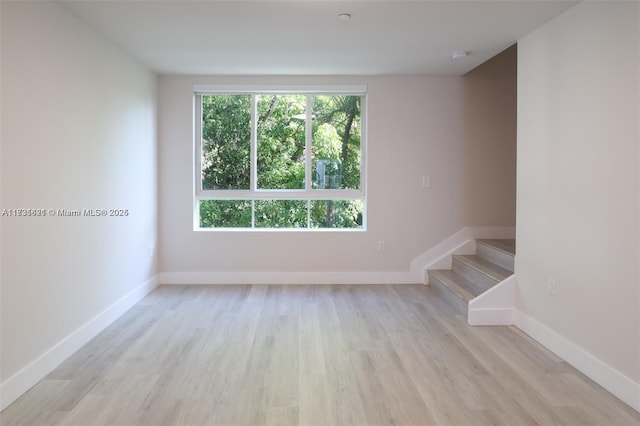 empty room with a wealth of natural light and light hardwood / wood-style flooring