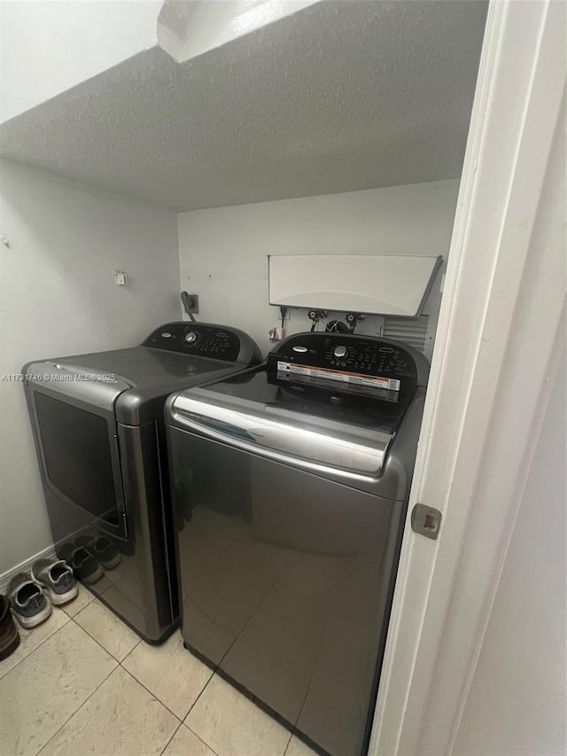 washroom with light tile patterned floors, washing machine and clothes dryer, and a textured ceiling