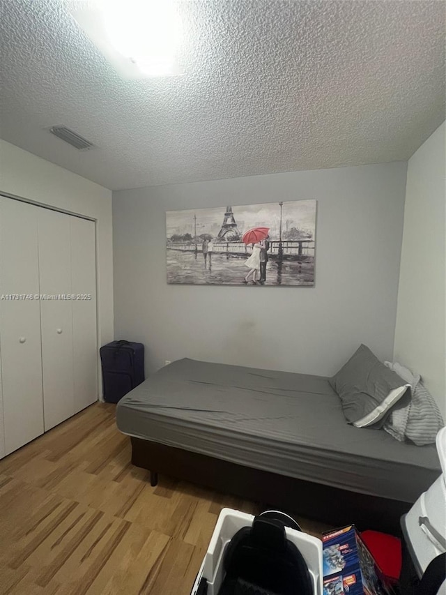 bedroom with hardwood / wood-style floors, a closet, and a textured ceiling