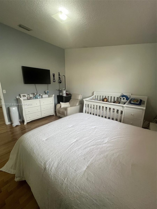 bedroom featuring dark hardwood / wood-style floors and a textured ceiling