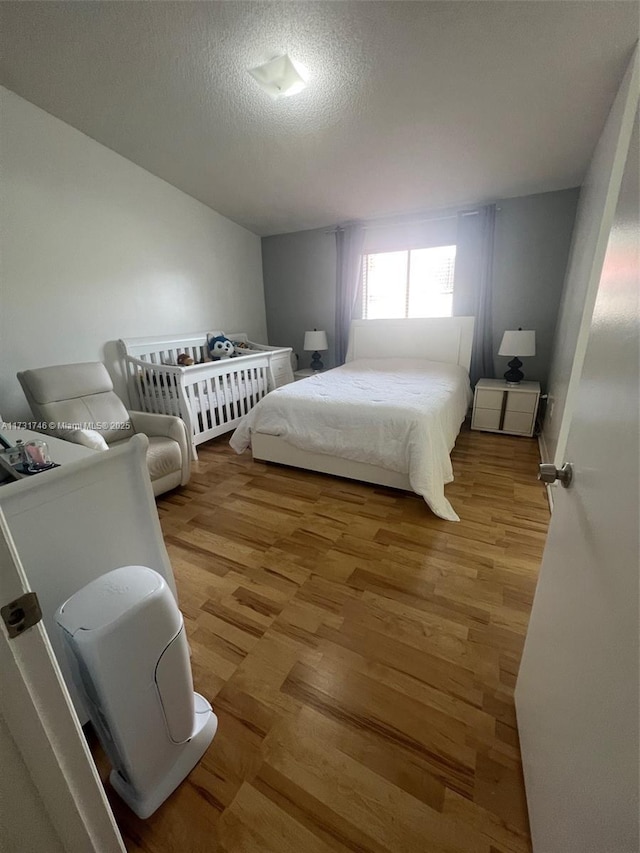 bedroom with a textured ceiling and light hardwood / wood-style floors