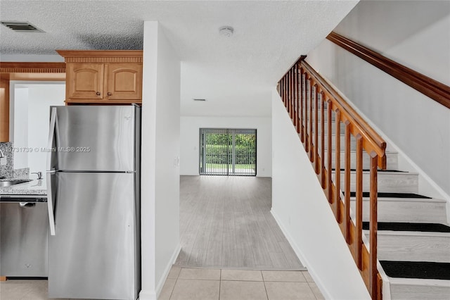 kitchen with sink, light tile patterned flooring, a textured ceiling, and appliances with stainless steel finishes