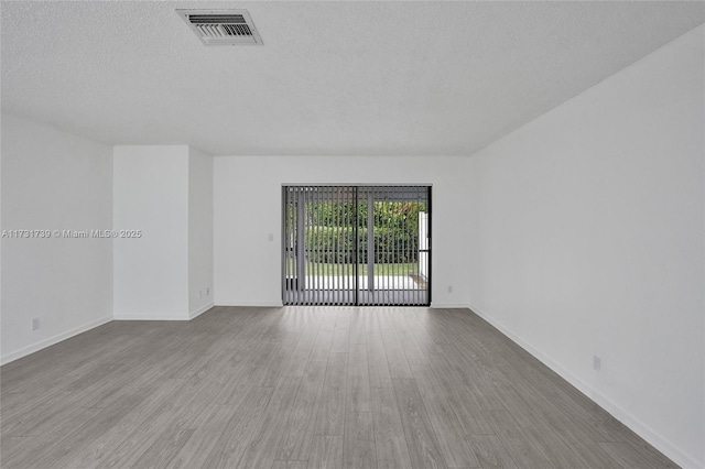 empty room with light hardwood / wood-style floors and a textured ceiling