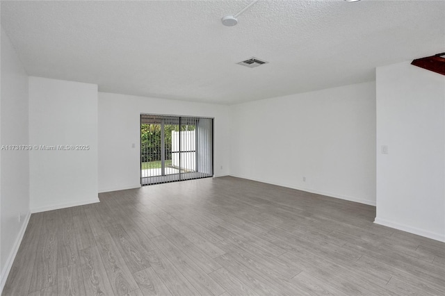 spare room featuring a textured ceiling and light wood-type flooring