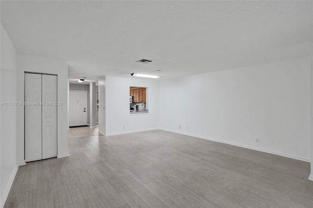 unfurnished room with a textured ceiling and light hardwood / wood-style floors