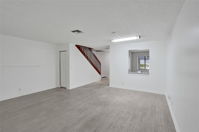 unfurnished room with light hardwood / wood-style floors and a textured ceiling