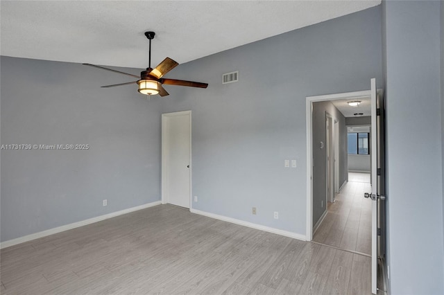 spare room featuring ceiling fan, lofted ceiling, a textured ceiling, and light wood-type flooring