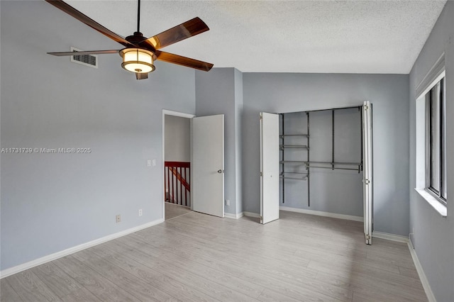 unfurnished bedroom with ceiling fan, high vaulted ceiling, a textured ceiling, and light wood-type flooring