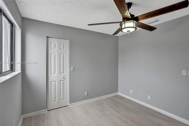 spare room featuring ceiling fan, a textured ceiling, and light wood-type flooring