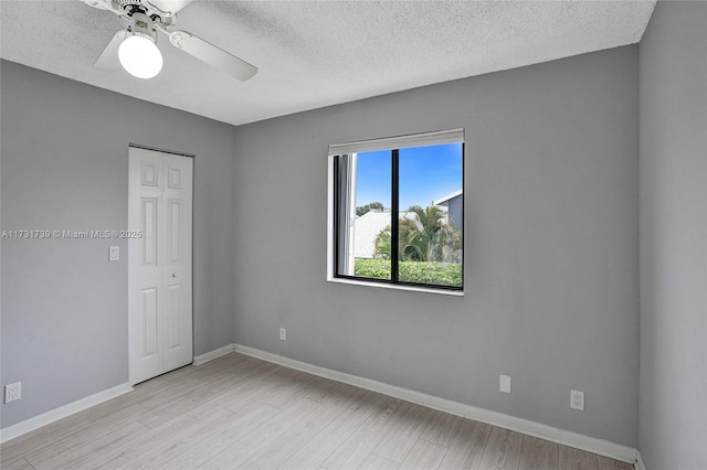 empty room featuring ceiling fan, a textured ceiling, and light hardwood / wood-style flooring