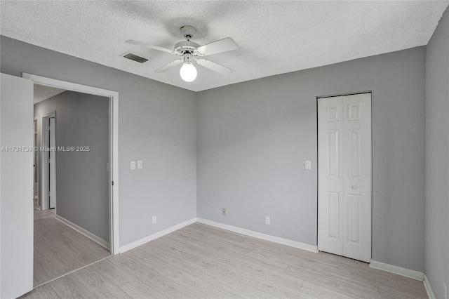 unfurnished room with ceiling fan, light hardwood / wood-style floors, and a textured ceiling