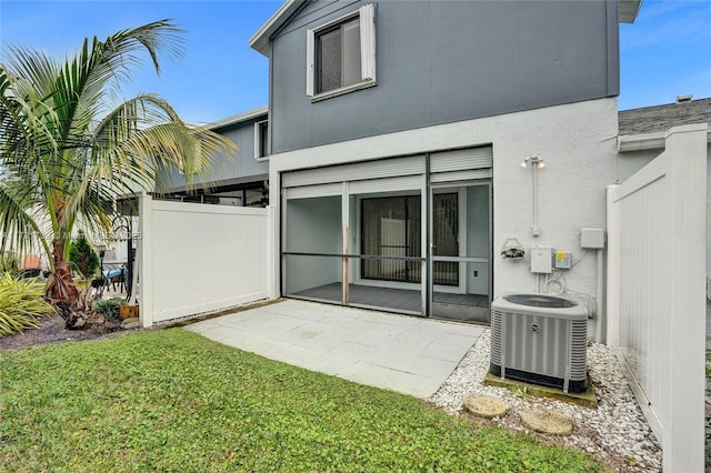 back of house featuring central AC unit, a patio area, and a lawn