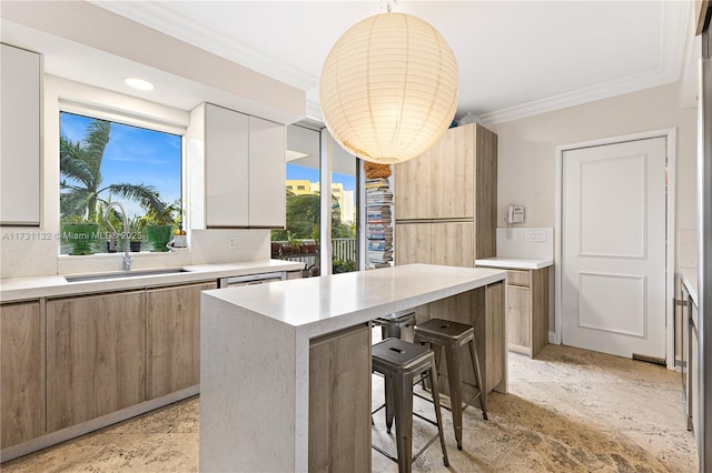 kitchen featuring a kitchen island, sink, white cabinets, a kitchen breakfast bar, and ornamental molding