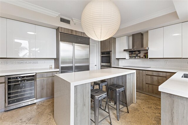 kitchen with wall chimney range hood, beverage cooler, white cabinets, and appliances with stainless steel finishes