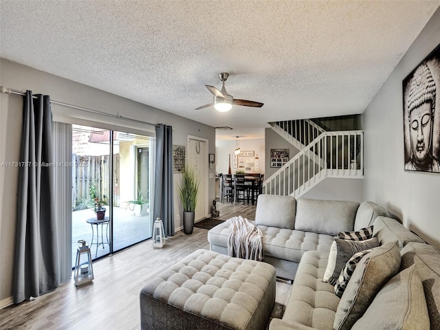 living room featuring ceiling fan, a textured ceiling, and light wood-type flooring