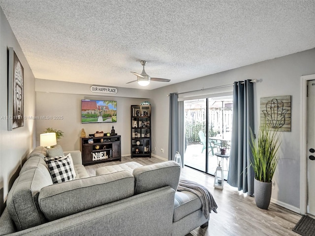 living room featuring ceiling fan, a textured ceiling, and light hardwood / wood-style flooring