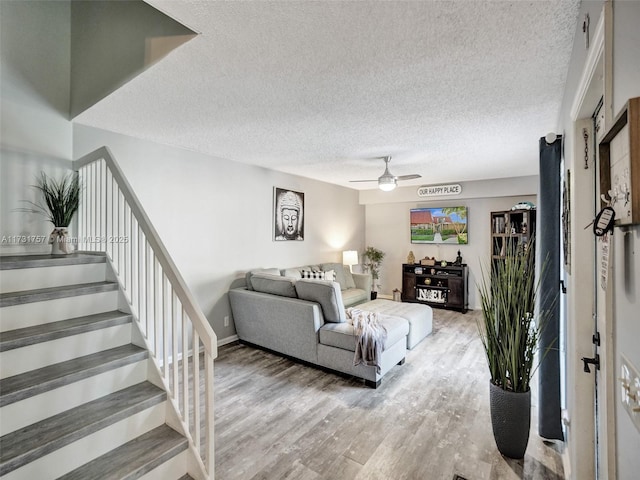 living room featuring ceiling fan, hardwood / wood-style floors, and a textured ceiling