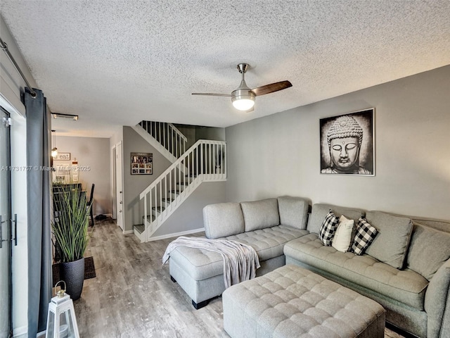 living room featuring ceiling fan, a textured ceiling, and light wood-type flooring