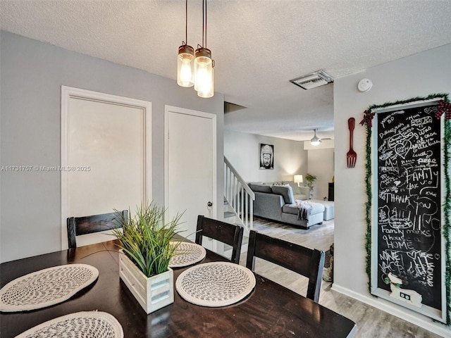 dining room featuring wood-type flooring and a textured ceiling