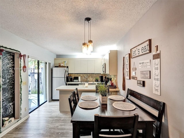 dining area featuring light hardwood / wood-style flooring and a textured ceiling