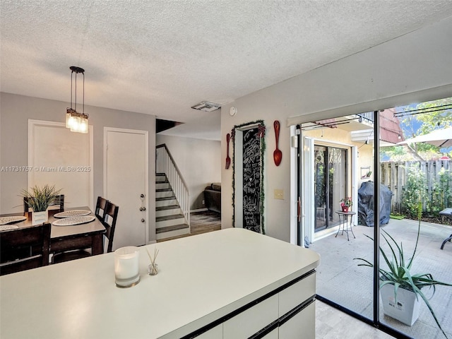 kitchen featuring pendant lighting, white cabinetry, and a textured ceiling