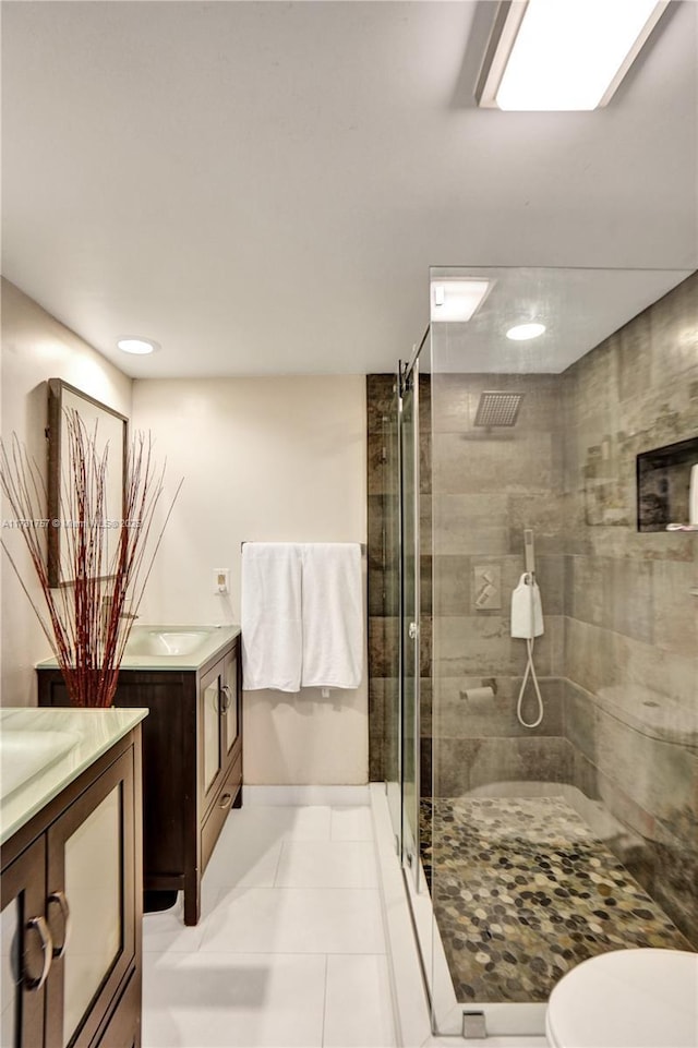 bathroom featuring toilet, vanity, tile patterned floors, and a shower with shower door