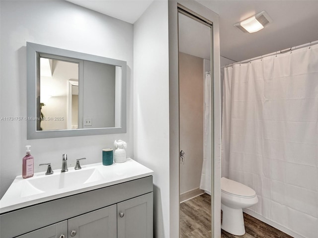 bathroom featuring hardwood / wood-style flooring, vanity, toilet, and curtained shower