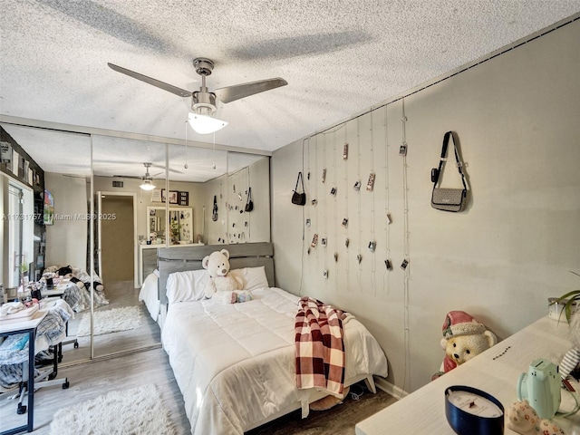 bedroom featuring hardwood / wood-style flooring, a textured ceiling, ceiling fan, and a closet