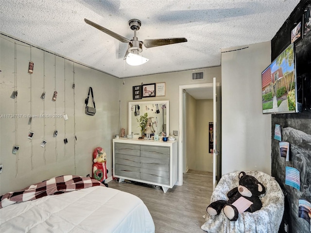 bedroom with hardwood / wood-style flooring, a textured ceiling, and ceiling fan