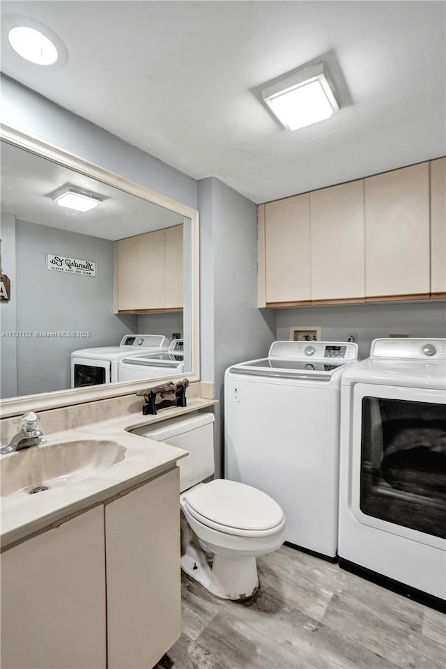 bathroom with wood-type flooring, vanity, washing machine and clothes dryer, and toilet