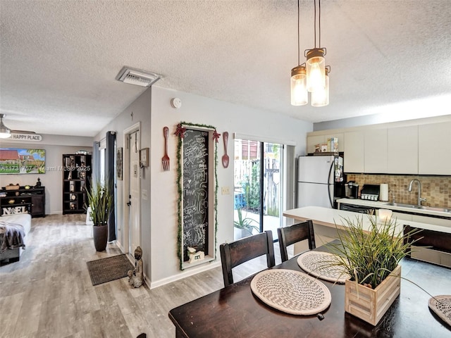 dining space featuring sink, a textured ceiling, and light hardwood / wood-style flooring