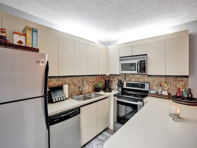 kitchen featuring sink, appliances with stainless steel finishes, white cabinetry, a textured ceiling, and decorative backsplash