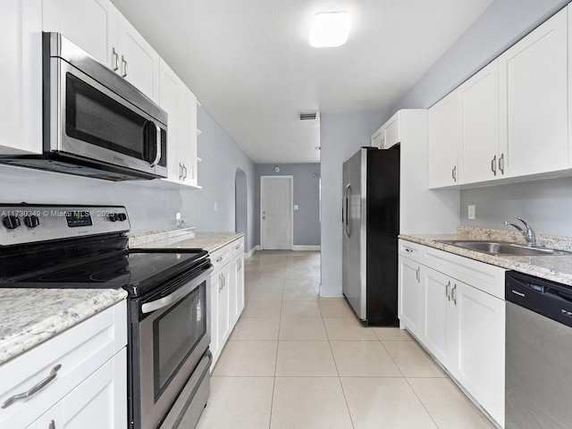 kitchen with stainless steel appliances, sink, light tile patterned floors, and white cabinets