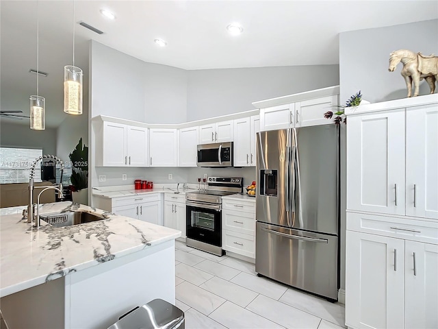 kitchen featuring white cabinetry, stainless steel appliances, decorative light fixtures, and sink