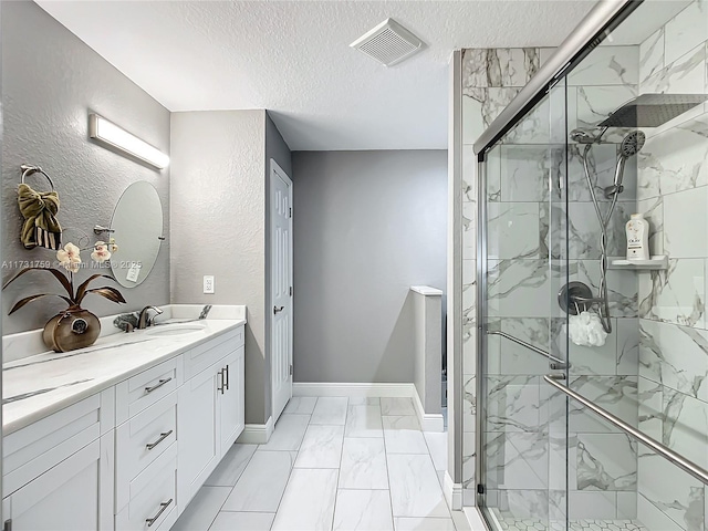 bathroom featuring a shower with door, vanity, and a textured ceiling