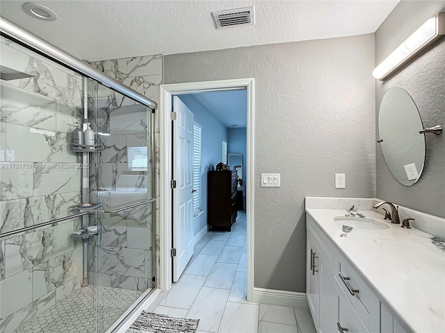 bathroom featuring vanity, a shower with door, and a textured ceiling