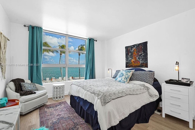 bedroom with a water view and hardwood / wood-style floors