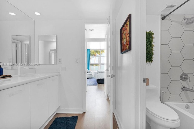 full bathroom with hardwood / wood-style floors, vanity, toilet, and shower / tub combination